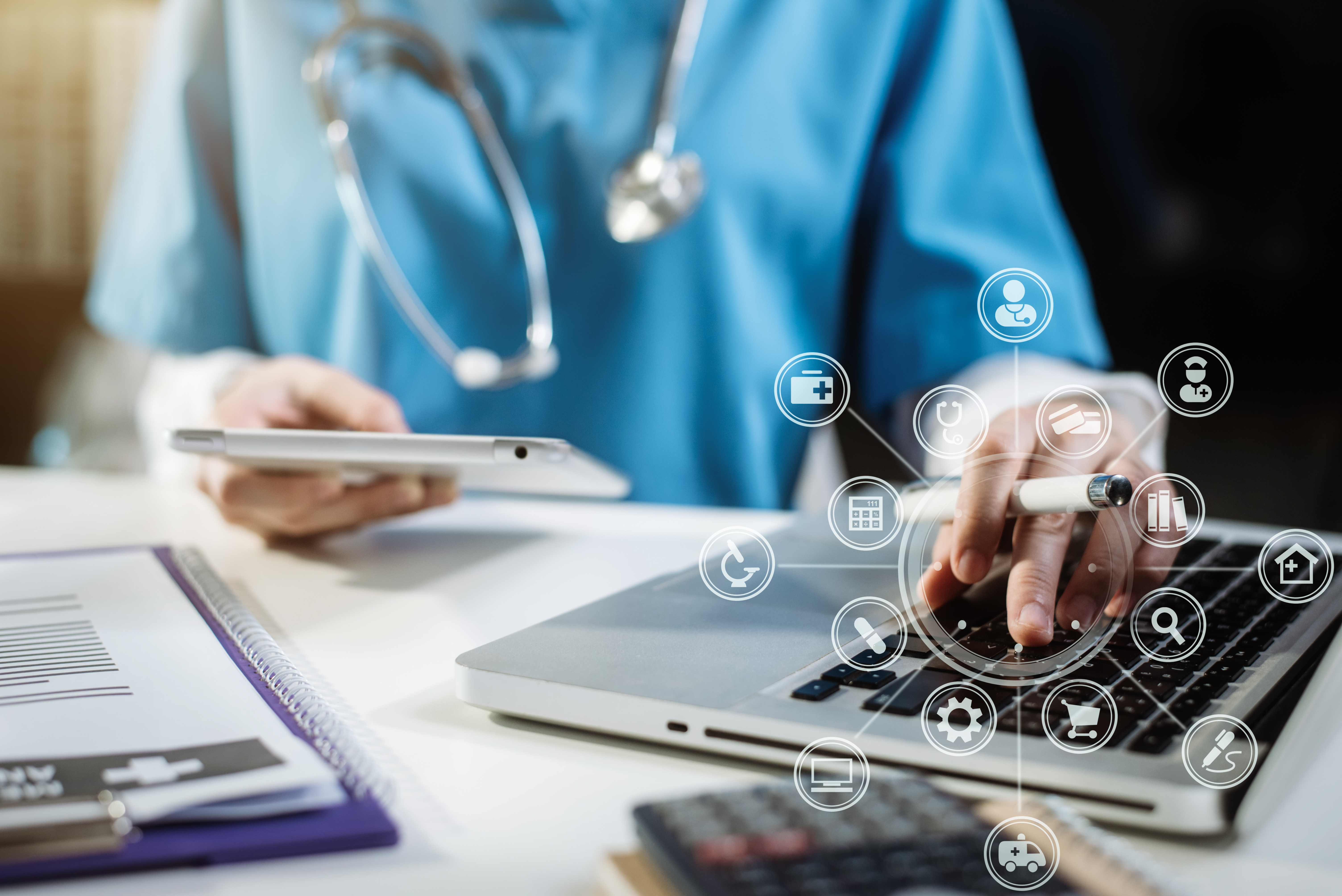 Image of a physician using a hand-held tablet and a laptop recording patient data