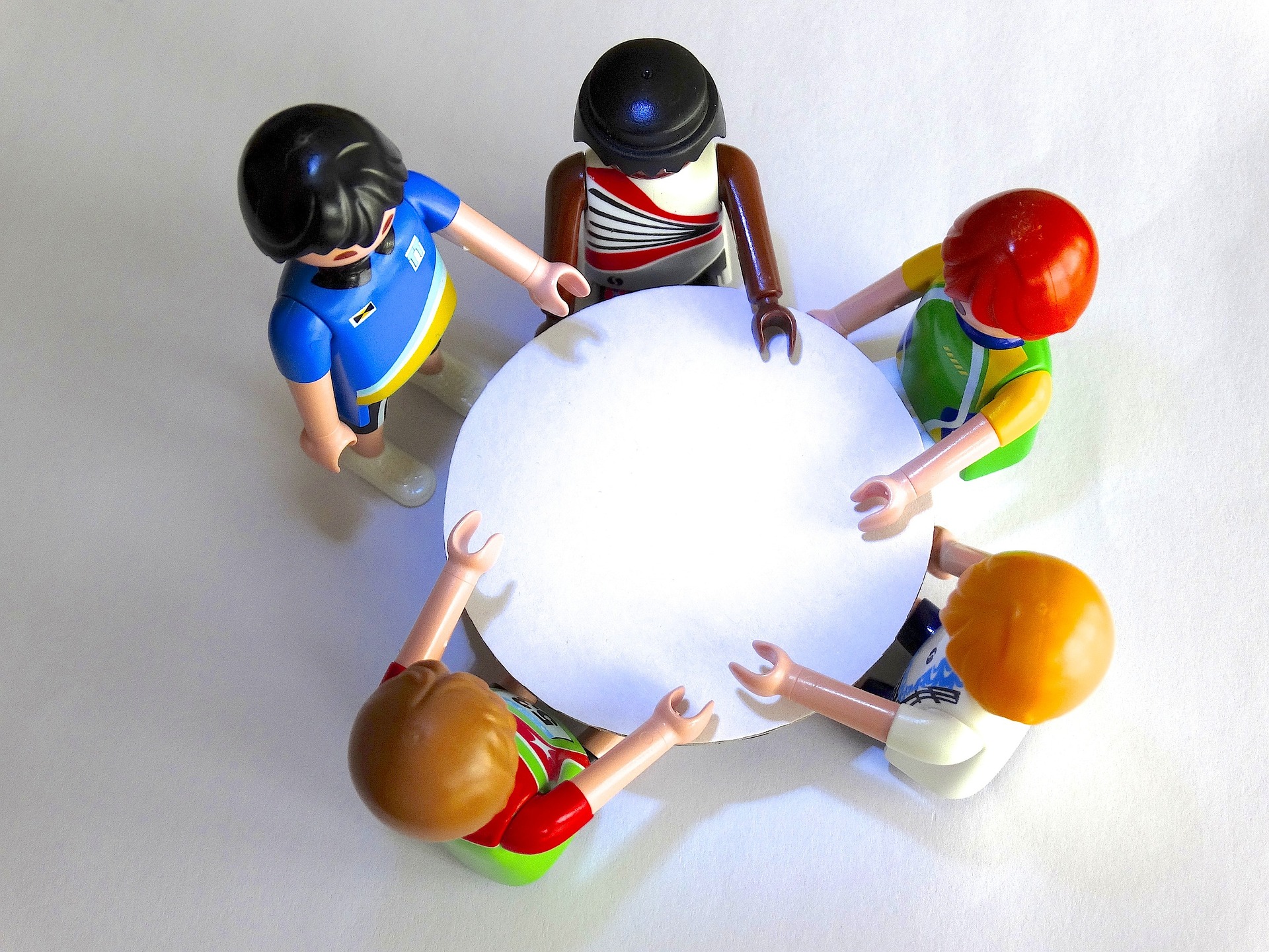 A group of playmobil toy figurines sit around a table, as viewed from above
