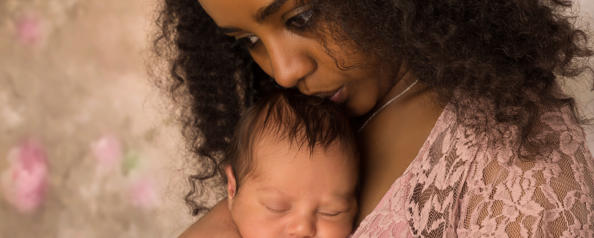 black mother holding newborn looking stressed