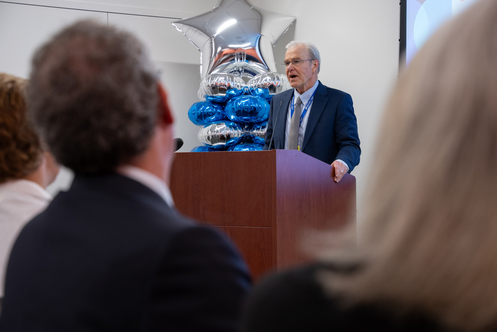 Dean Flotte welcoming the new medical students and thanking them for the opportunity for a shared learning experience. He is at a podium, speaking into a microphone.