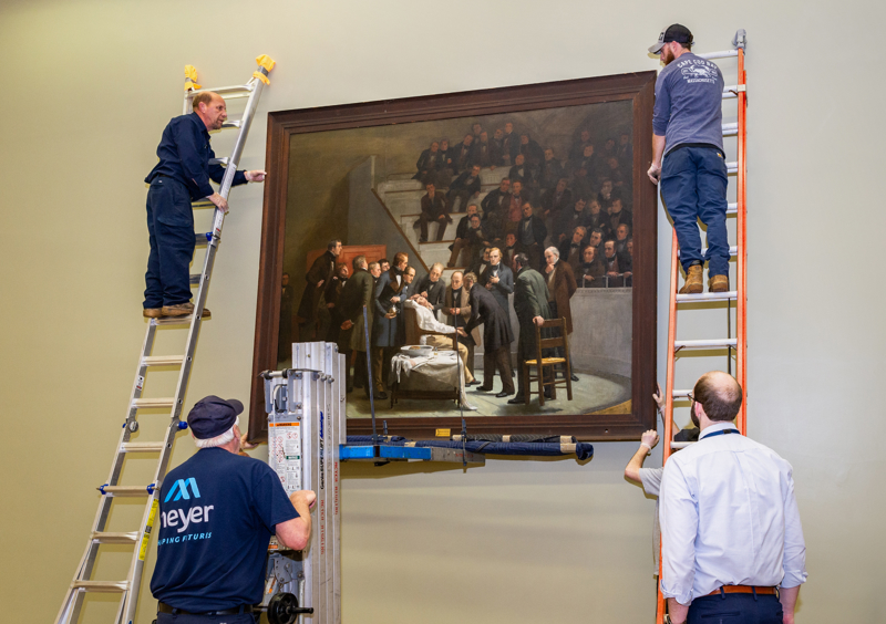 The historic painting “The First Operation Under Ether,” by Robert C. Hinckley, being installed in the Lamar Soutter Library in January. It is on long-term loan from Boston Medical Library. The painting depicts a crowded surgery suite with a patient being administered anesthesia.