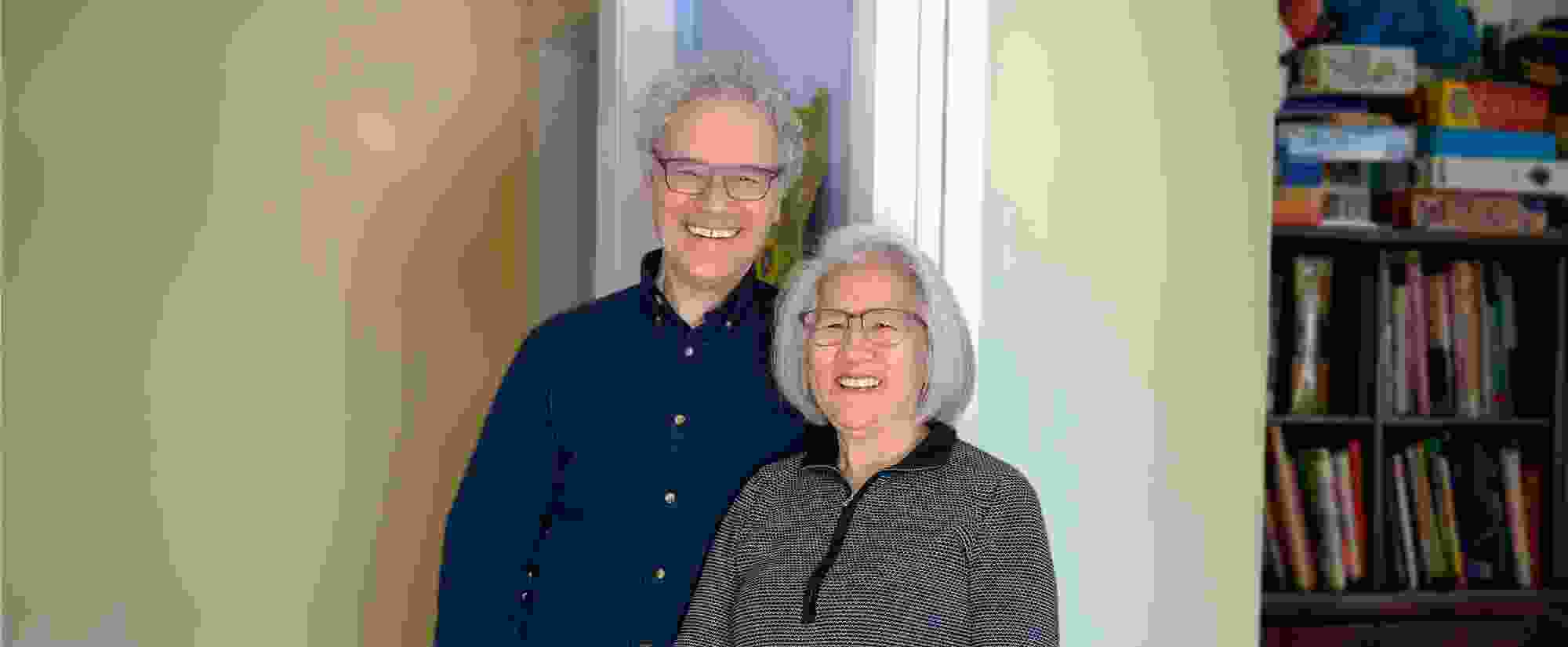 Photograph of Victor Ambros and Rosalind Lee standing side-by-side, smiling and looking into the camera.