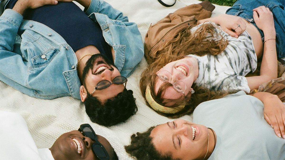 group of young adults lying on a picnic blanket