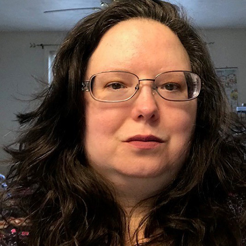 white woman with black long wavy hair and glasses